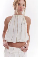 Blusa crop estilo halter con diseño abullonado en la parte inferior, confeccionada en lino con estampado de rayas verticales sutiles.