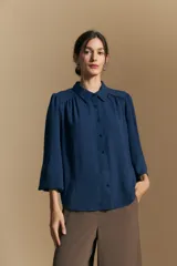 Camisa de manga larga con caída fluida, diseño de silueta suelta, cuello clásico y cierre frontal con botones.