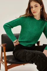 Sweater de punto color verde con diseño de ondas en relieve y sutiles destellos de lentejuelas integradas. Presenta cuello redondo, mangas largas y puños acanalados.