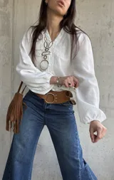 Camisa blanca de manga larga abullonada, con delicados bordados frontales y cierre con botones.