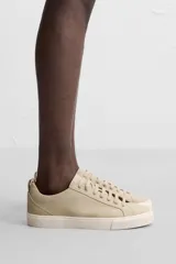 Zapatilla de cordones color beige, con parte superior lisa, horma redonda, forro interior a contraste y suela con ligera textura.