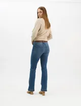 Jean de tiro alto con corte bootcut, color azul medio, con diseño de cinco bolsillos y costuras en contraste. Incluye un cinturón trenzado de cuero sintético con hebilla metálica.