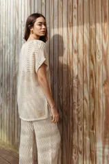 Pantalón de tiro alto, color crudo, tejido con hilo de algodón en punto pavo real y corte holgado.