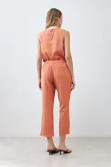 Pantalón capri color durazno de lino con efecto desflecado en el ruedo.