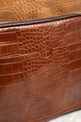 Mochila marrón con estampado de piel de cocodrilo, con cierre superior y bolsillo frontal con cierre.