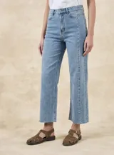 Jean de corte recto y tiro medio, confeccionado en denim de algodón con un toque de elastano. Presenta costuras verticales decorativas a lo largo de las piernas y un ruedo deshilachado.