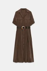 Vestido midi de corte fluido en color marrón, con cuello solapa, escote en pico y cierre frontal de botones. Presenta mangas cortas con dobladillo, bolsillos delanteros y un cinturón trenzado con hebilla redonda de madera.