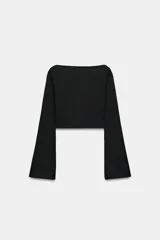 Camiseta de cuello barco y manga larga con diseño asimétrico en el bajo. Presenta un corte entallado con cierre lateral mediante cremallera oculta.