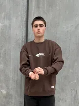 Buzo marrón de algodón con cuello redondo, puños y cintura acanalados. Estampa frontal con el logo de la marca en color blanco.