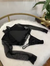Conjunto de lencería compuesto por un top de cuello alto con mangas largas de microtul y detalles de encaje, y una tanga regulable de terciopelo y encaje.