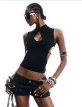 Top ajustado negro sin mangas, con cuello alto, abertura cut-out en el escote y laterales descubiertos con tiras finas cruzadas.