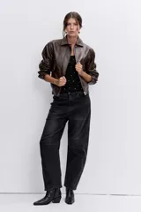 Cazadora de efecto piel en color marrón chocolate, con cuello clásico, cierre frontal con cremallera, bolsillos laterales y puños con botón.