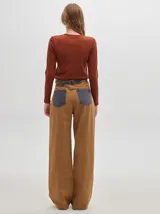 Pantalón jean de tiro alto y corte pinzado, con perneras de caída suelta y levemente anchas en el bajo. Posee pasador con hebilla en la parte trasera.