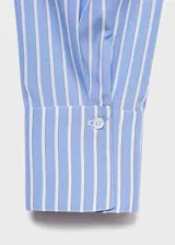 Blusa de manga larga con diseño de rayas verticales en tonos azul y blanco. Presenta un cuello redondo con un pañuelo integrado que cae sobre el pecho y puños abotonados.