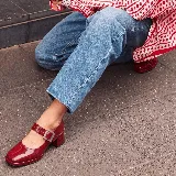 Zapato Mary Jane de cuero charolado en color bordó, con tira en el empeine con hebilla metálica rectangular, taco ancho y punta cuadrada.