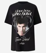Remera negra de algodón con cuello redondo y manga corta. Presenta un estampado frontal con la imagen de Jacob Black de la saga Crepúsculo dentro de un corazón de puntos, acompañado por el texto 'I love boys who howl' y 'Team Jacob'.