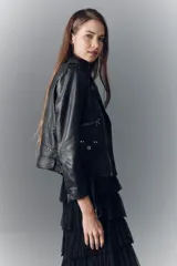 Campera estilo biker confeccionada en cuero ovino, con solapas amplias, charreteras en los hombros y múltiples cierres metálicos frontales. Presenta un diseño ajustado con detalles de herrajes plateados y forro interior de poliéster.