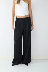 Pantalón de vestir negro de tiro alto con pliegues frontales, corte amplio y pernera recta. Cuenta con bolsillos laterales y cierre frontal con cremallera y botón.