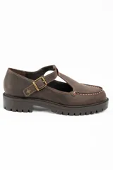 Zapato tipo guillermina de cuero lavado color marrón, con diseño de tira en T y cierre de hebilla metálica. Presenta costuras decorativas en contraste y suela de goma con plataforma dentada.