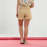 Short color beige de tiro alto con pinzas delanteras, bolsillos laterales y cierre frontal con botón.