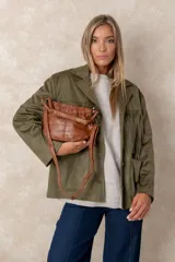 Cartera de mano con acabado envejecido y brillante, diseño de cuerpo suave con fruncido en la parte superior. Incluye correa larga ajustable y herrajes metálicos oscuros.