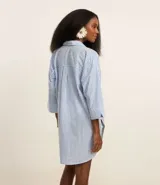 Salida de playa tipo camisa confeccionada en voile de algodón BCI con estampado de rayas verticales, cuello camisero, mangas largas y abotonado delantero.