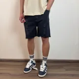 Bermuda de jean negro con efecto desgastado y roturas, corte tipo jogger con cintura elástica y ruedo desflecado.