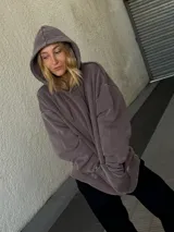 Buzo canguro marrón con capucha y cordones, de corte amplio y estilo urbano.