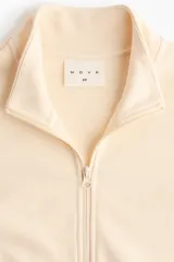 Campera deportiva de felpa de algodón color beige, de corte ajustado, con cuello elevado, cierre frontal y bolsillos laterales discretos. Presenta puños y bajo acanalados.