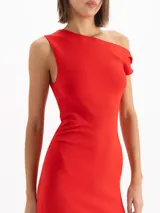 Vestido largo negro de corte sirena con escote asimétrico caído en un hombro. Presenta falda con paneles transparentes y plisados verticales a partir de las rodillas.