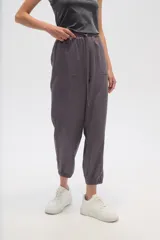 Pantalon de corte relajado, color gris, con cintura elástica y cordón ajustable. Presenta bolsillos frontales tipo parche y puños elásticos en los tobillos.