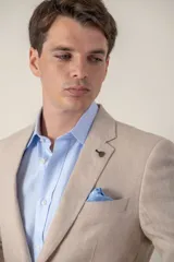 Saco de lino corte slim fit, color beige, con solapa de muesca, cierre frontal de dos botones y bolsillos con solapa.