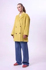 Tapado de lana color mostaza, de corte recto y diseño cruzado con botones frontales. Presenta solapas clásicas, mangas largas y bolsillos laterales.