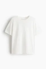 Remera de punto suave de algodón, de color blanco, con cuello redondo ribeteado y acanalado, corte holgado, hombros caídos y mangas cortas con doblez cosido.