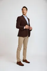 Blazer de pana color marrón oscuro, con cierre frontal de dos botones, solapas clásicas y bolsillos laterales con solapa. Presenta un diseño estructurado y elegante.