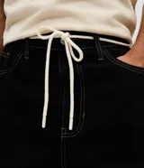 Pantalón masculino de corte baggy, confeccionado en sarga de algodón. Presenta un diseño holgado con costuras en contraste, cierre tradicional y cordón ajustable en la cintura.