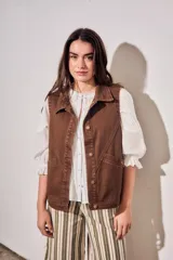 Chaleco oversize de algodón color marrón con efecto lavado, cuello solapa y cierre frontal con botones metálicos. Cuenta con bolsillos frontales diagonales.