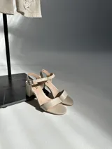 Sandalias de taco cuadrado y altura media, con tira delantera y tira ajustable al tobillo con hebilla metálica.