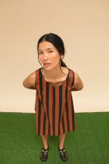 Vestido corto a rayas verticales en tonos marrón, negro y naranja. De corte recto, sin mangas y con cuello redondo. Confeccionado en algodón.