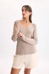 Sweater de punto color beige con hilos de lurex, escote en V y mangas largas con costuras en los hombros.