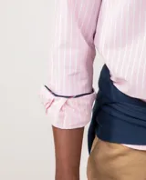 Camisa de hombre Oxford a rayas rosadas y blancas, con corte regular fit, cuello button-down, mangas largas, cierre frontal de botones y logo bordado en el pecho.