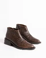 Bota corta de cuero vacuno con acabado metalizado y textura de reptil. Presenta punta fina, cierre lateral interno y taco cuadrado de madera.