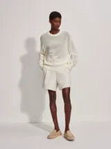 Sweater de punto calado color crema, de corte holgado y cuello redondo.