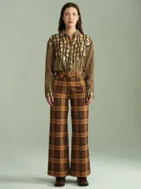 Pantalón de tiro alto con corte ancho y recto, confeccionado en tela de algodón con estampado de cuadros escoceses en tonos azul marino, verde y rojo. Presenta cierre frontal oculto con botones internos y pasacintos en la cintura.