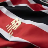 Remera de fútbol New Balance del São Paulo FC, modelo Home 2025. Diseño a rayas verticales rojas, blancas y negras con mangas rojas y detalles dorados en cuello y puños. Incluye logo de New Balance, escudo del club y sponsor Superbet en el frente.