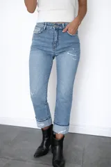 Pantalón de jean corte regular fit en color celeste claro. Presenta un diseño con pequeñas roturas frontales y botamanga con doblez, confeccionado en denim con elastano para mayor flexibilidad y comodidad.