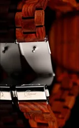 Reloj de pulsera con caja, esfera y malla de madera de sándalo rojo, con marcadores y manecillas negras. Presenta un diseño circular con corona lateral.