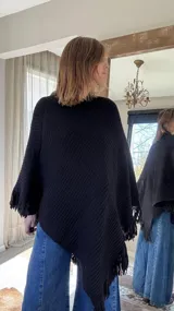 Poncho tejido en lana merino color marrón, con diseño de punto acanalado y terminación con flecos en el borde inferior. Incluye una pequeña etiqueta de cuero en la parte posterior.