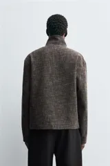 Sobrecamisa de corte relajado confeccionada en tejido con viscosa, de color gris oscuro con textura. Presenta cuello subido, cierre frontal con cremallera y bolsillos de vivo en la cadera.