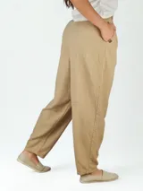 Pantalón de lino color beige, de corte recto, con pinzas en la cintura y bolsillos laterales.